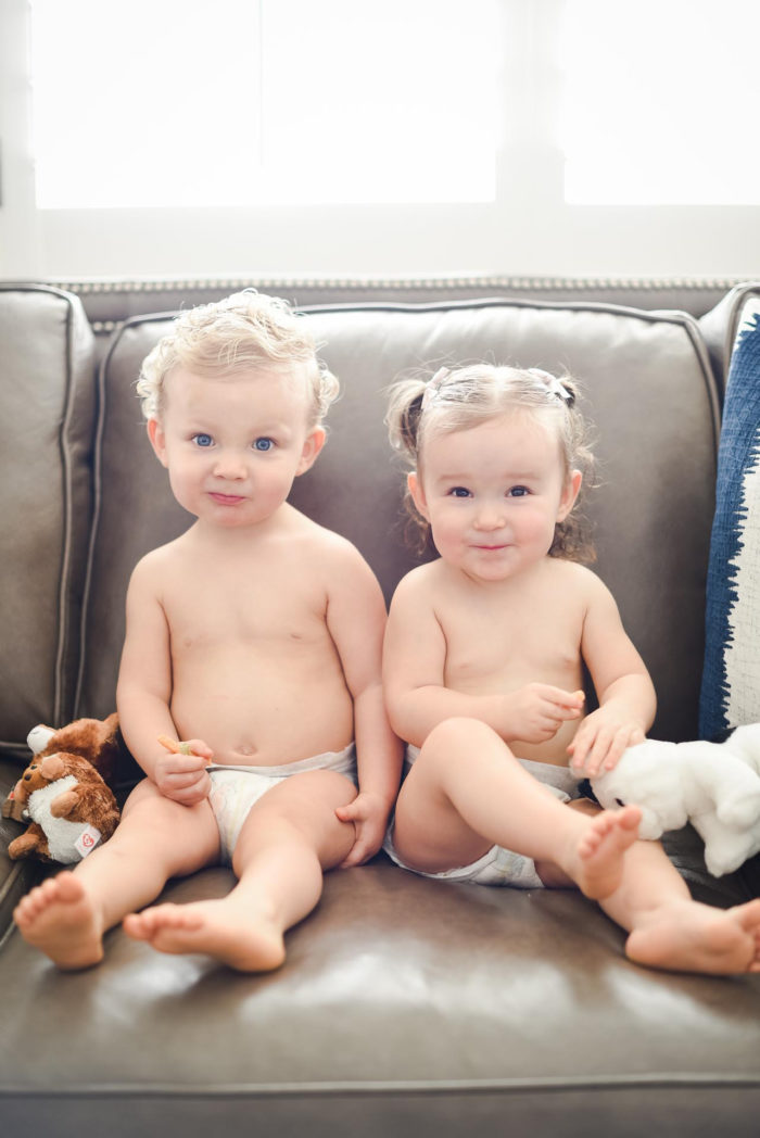Walmart Baby Registry Must-Have by popular Utah life and style blog, A Slice of Style: image of fraternal boy and girl twins wearing only diapers and sitting on a couch with their stuffed animals.