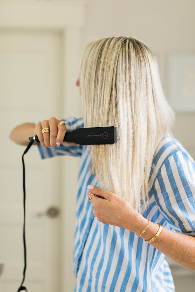 How to Curl Long Hair FAST & Keep your Hair Healthy featured by top Utah beauty blog, A Slice of Style: image of a woman holding hair straighteners