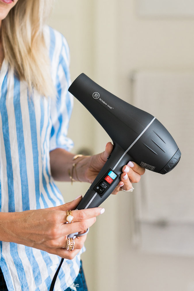 How to Curl Long Hair FAST & Keep your Hair Healthy featured by top Utah beauty blog, A Slice of Style: image of a woman holding hair care products to curl her long hair