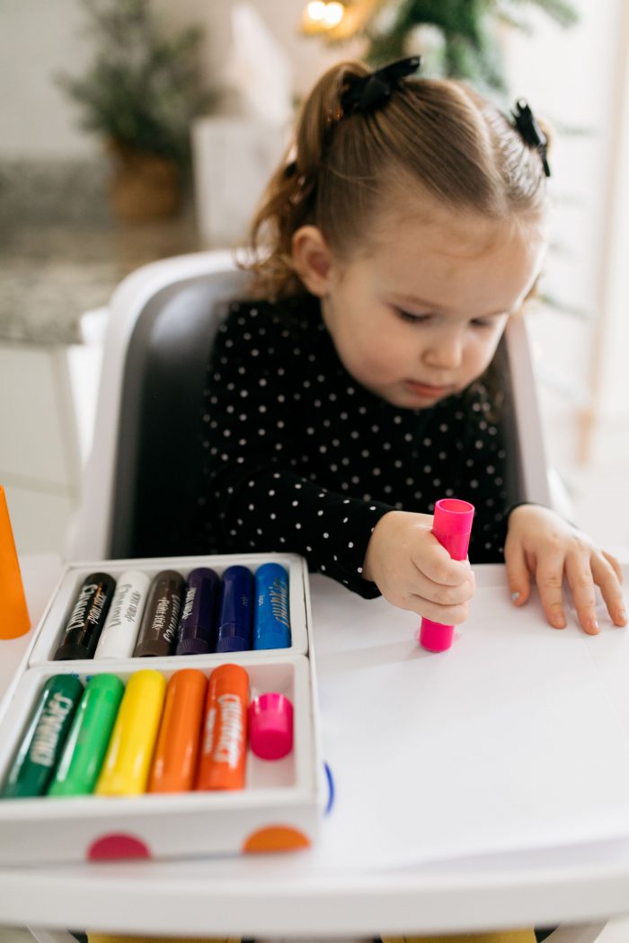 Fun Activities for Kids at Home by popular Utah lifestyle blog, A Slice of Style: image of a little girl sitting in her high chair and playing with some stamp markers. 