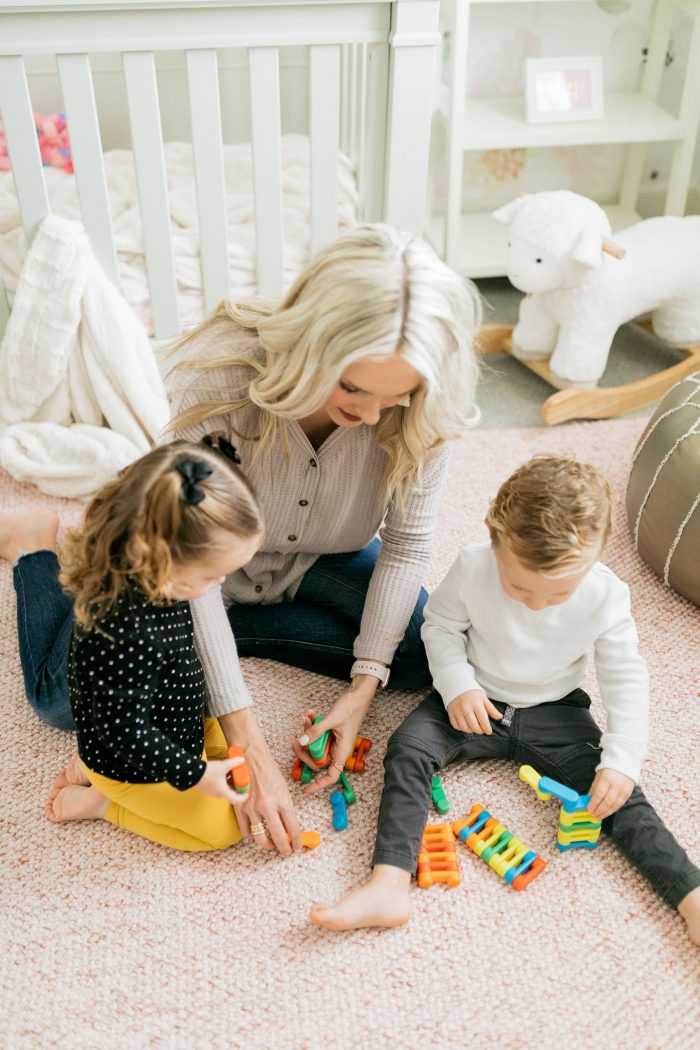 Fun Activities for Kids at Home by popular Utah lifestyle blog, A Slice of Style: image of a mom sitting on the floor with her twin children and playing with toys. 