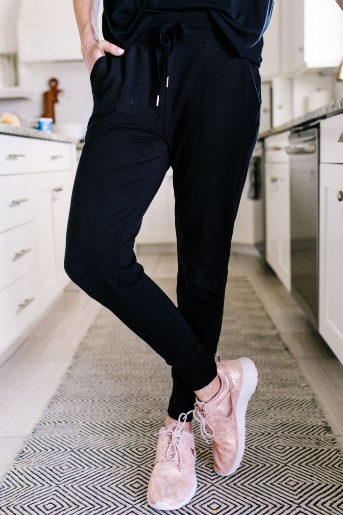 Most Popular Products featured by top US life and style blog A Slice of Style; Image of a woman wearing Nike shoes, black shirt and black joggers.