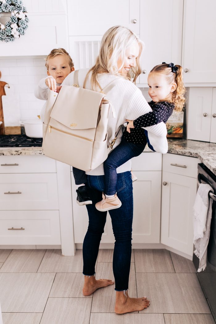 Freshly Picked Coupon Code! by popular Utah fashion blog, A Slice of Style: image of a woman holding her twin kids and wearing a Freshly Picked Diaper bag back pack. 