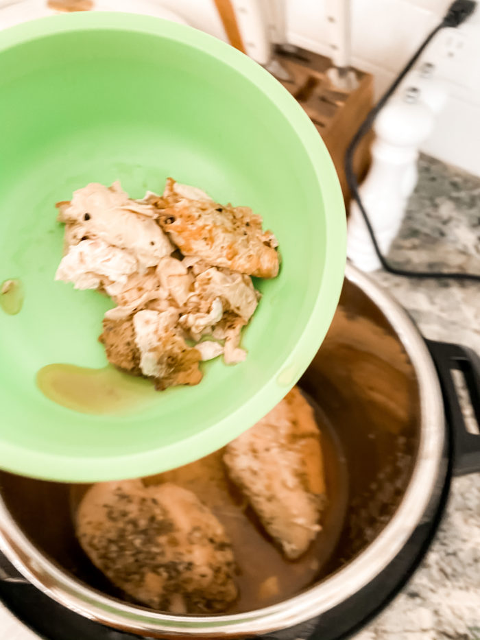 instant pot chicken | Instant Pot Chicken by popular Utah lifestyle blog, A Slice of Style: image of a woman holding a green plastic bowl with chicken fat in it over a open Instant Pot with cooked chicken in it. 