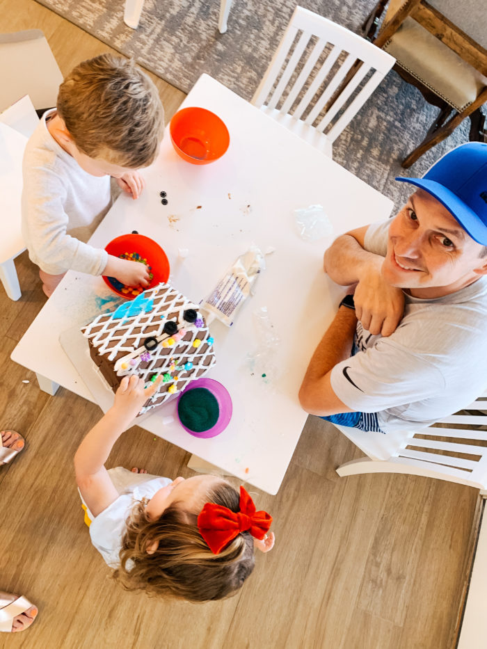 Easter Essentials by popular Utah lifestyle blog, A Slice of Style: image of a dad decorating a Easter gingerbread house with his twin children. 