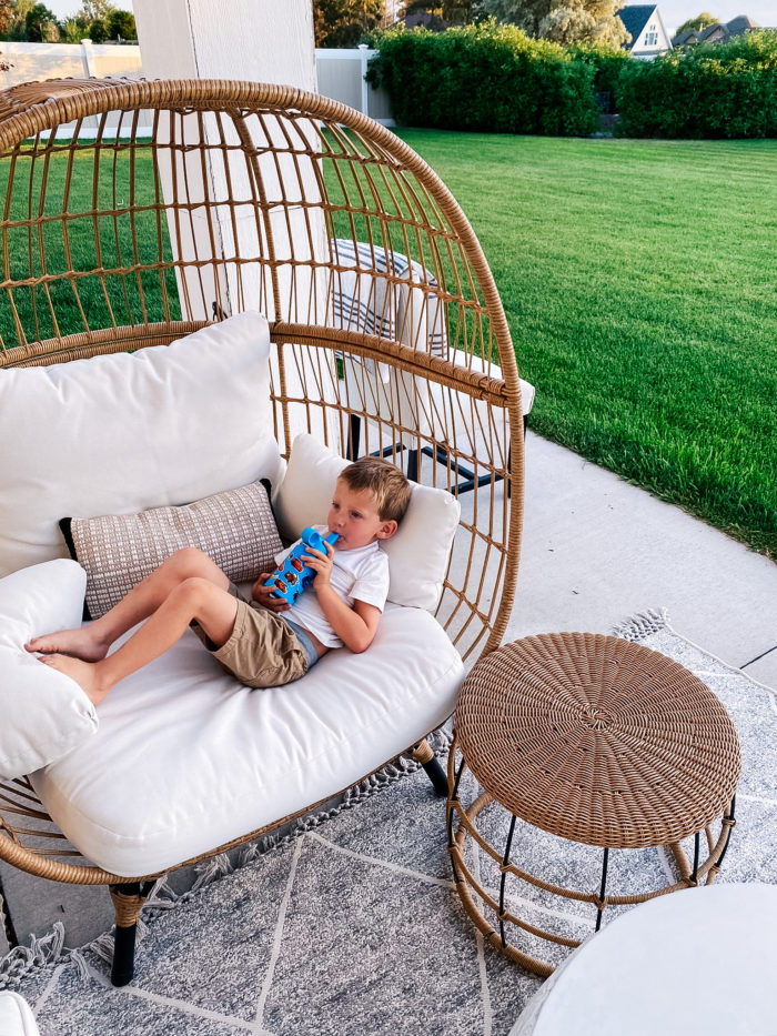 White Outdoor Cushions by popular Utah life and style blog, A Slice of Style: image of a little boy drinking out of a water bottle while he lays down on some white outdoor cushions. 