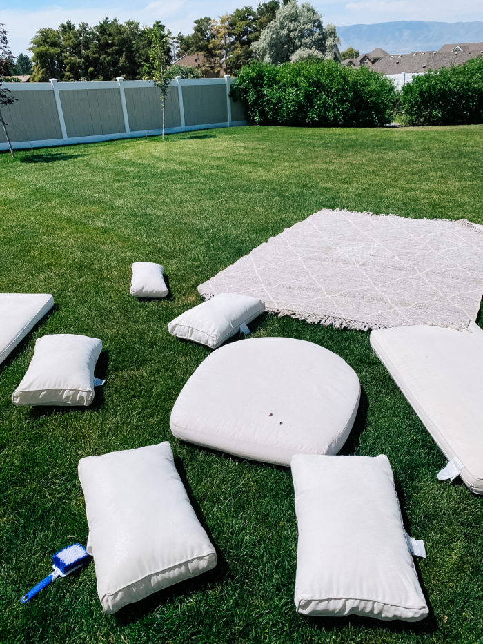 White Outdoor Cushions by popular Utah life and style blog, A Slice of Style: image of a white outdoor cushions and a grey and white outdoor rug spread out on the grass. 