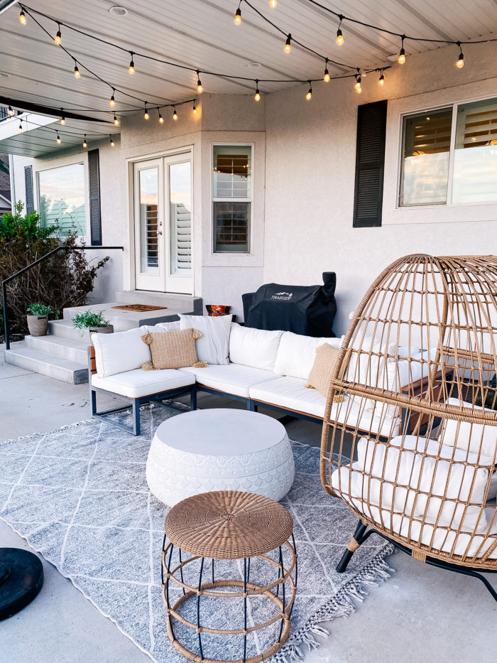 White Outdoor Cushions by popular Utah life and style blog, A Slice of Style: image of a backyard patio with bistro lights, white shade umbrellas, patio furniture and white outdoor cushions. 