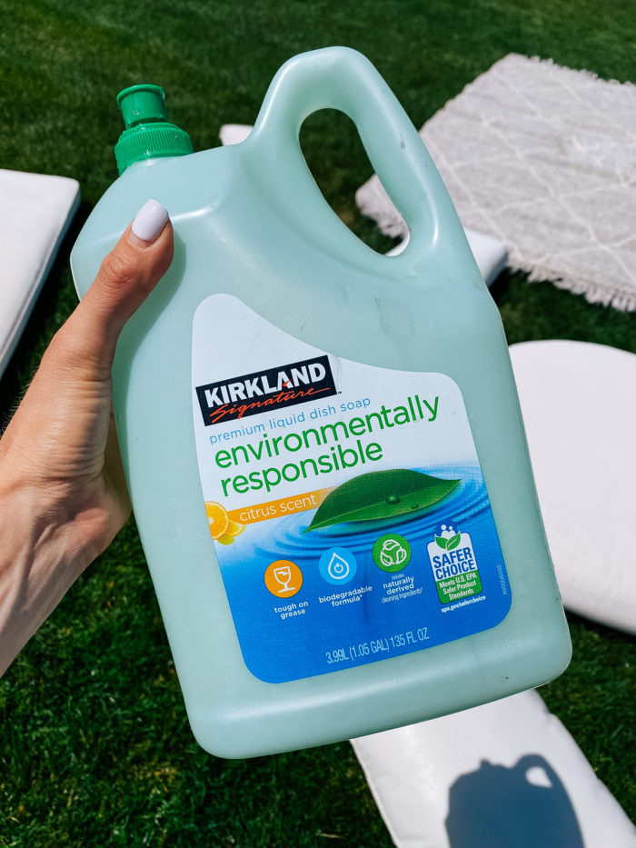White Outdoor Cushions by popular Utah life and style blog, A Slice of Style: image of Jenica Parcell holding a bottle of Kirkland Signature Environmentally Responsible liquid dish soap. 