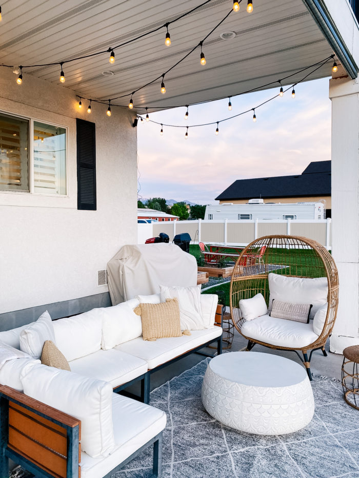 White Outdoor Cushions by popular Utah life and style blog, A Slice of Style: image of a backyard patio with bistro lights, patio furniture and white outdoor cushions. 