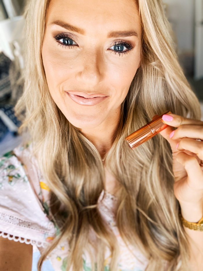 Best Lip Products by popular Utah beauty blog, A Slice of Style: image of Jenica Parcell wearing a pink floral dress and holding a Nordstrom Hot Lips Lipstick CHARLOTTE TILBURY.