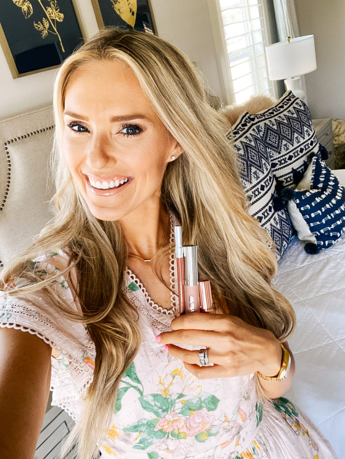 Best Lip Products by popular Utah beauty blog, A Slice of Style: image of Jenica Parcell wearing a pink floral dress and holding a Nordstrom 24/7 Glide-On Lip Pencil URBAN DECAY, Nordstrom Hot Lips Lipstick CHARLOTTE TILBURY, and Nordstrom Full-On™ Plumping Lip Cream BUXOM.