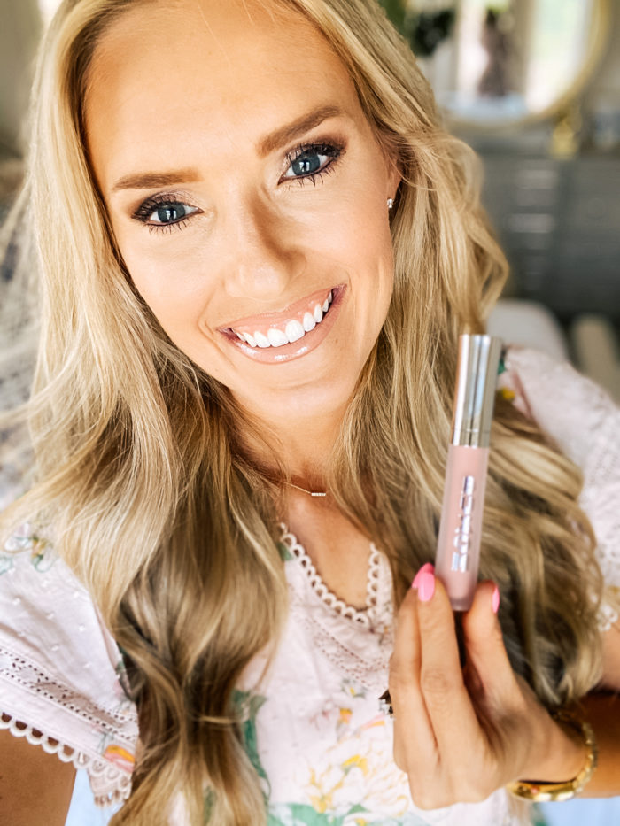 Best Lip Products by popular Utah beauty blog, A Slice of Style: image of Jenica Parcell wearing a pink floral dress and holding a Nordstrom Full-On™ Plumping Lip Cream BUXOM.