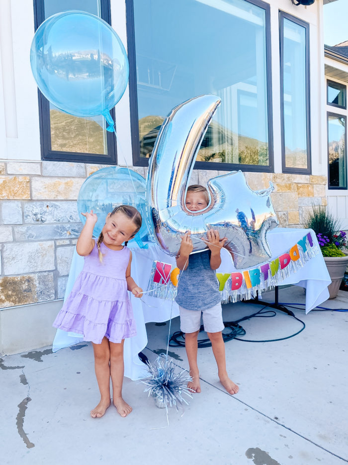 4th Birthday Party by popular Utah motherhood blog, A Slice of Style: image of boy and girl twins holding a birthday balloon bouquet together. 