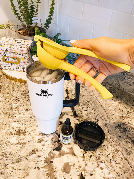 Stanley Travel Mug by popular Utah lifestyle blog, A Slice of Style: image of Jenica Parcell squeezing a lemon into a white Stanley travel mug.