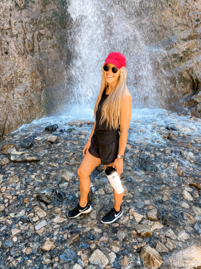 Epstein-Barr Virus by popular Utah lifestyle blog, A Slice of Style: image of Jenica Parcell holding a Stanley ADVENTURE QUENCHER TRAVEL TUMBLER and standing next to a waterfall. 